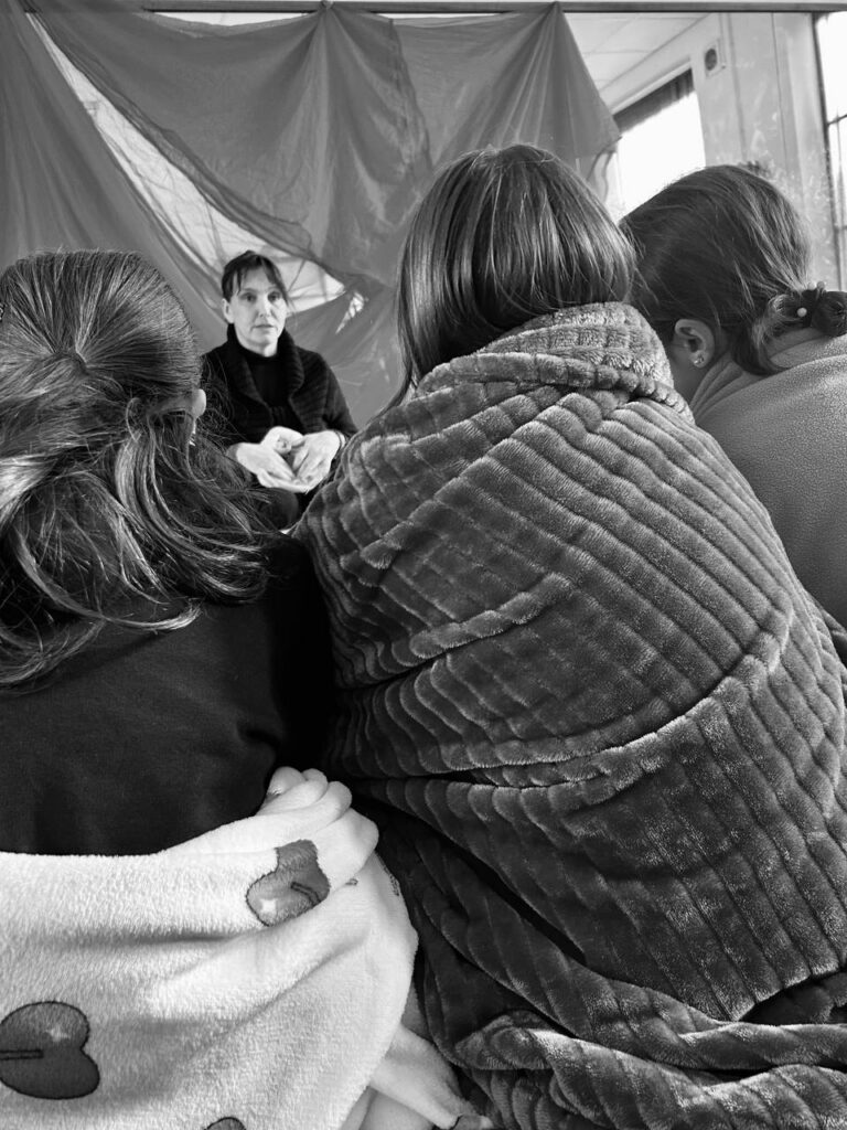 Educatrice che guida un laboratorio della Fata del Grembo con bambine e mamme, in un ambiente interattivo e accogliente."