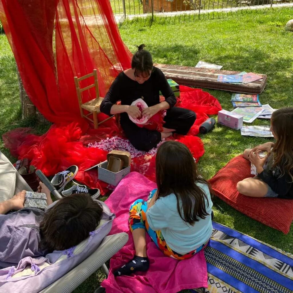 Educatrice che guida un laboratorio della Fata del Grembo con bambine e mamme, in un ambiente interattivo e accogliente."