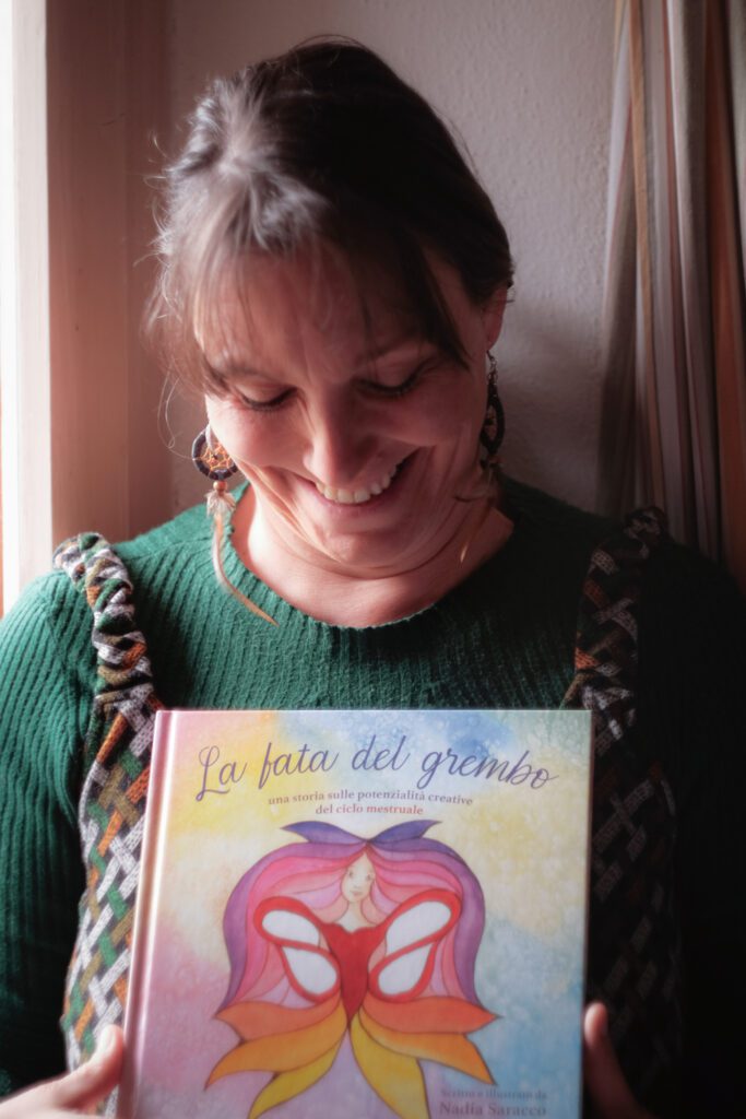 Immagine di Nadia Saracco con il libro "La Fata del Grembo": Nadia Saracco sorride mentre tiene in mano il suo libro "La Fata del Grembo"